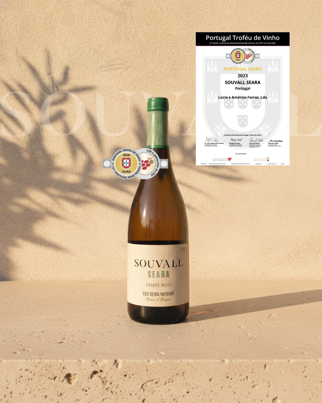 Garrafa de vinho branco Souvall Seara DOC Beira Interior sobre base de pedra clara, acompanhada pelo certificado e selo de Medalha de Ouro no concurso Portugal Troféu de Vinho 2026.