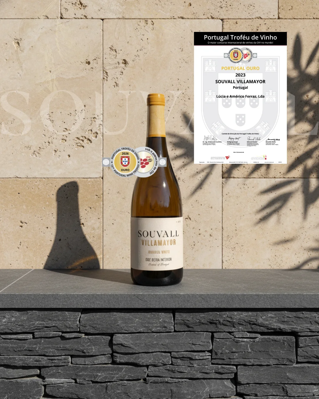 Garrafa de vinho Souvall Villamayor Branco pousada sobre murete de xisto e pedra clara, com destaque para o selo e o diploma de Medalha de Ouro do Portugal Troféu de Vinho 2026.