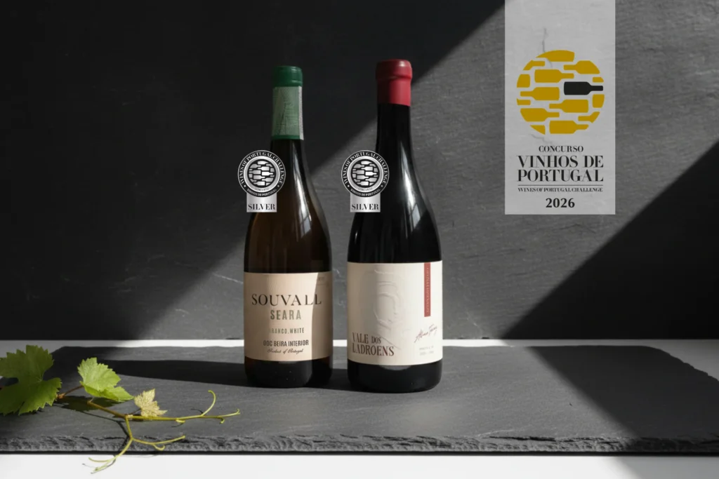 Garrafas dos vinhos de altitude Souvall Seara Branco e Vale dos Ladrões Garrafeira Tinto com medalhas de prata do Concurso de Vinhos de Portugal 2026 sobre placa de xisto.