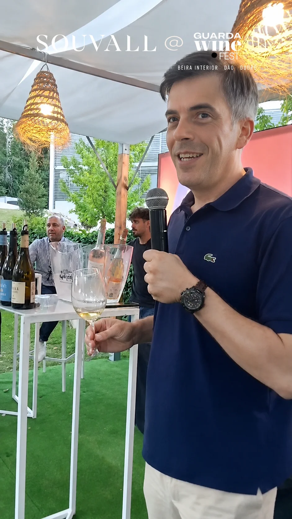 O Master of Wine Tiago Macena a discursar com microfone numa mão e um copo de vinho na outra, durante a sua apresentação no evento Guarda Wine Fest.