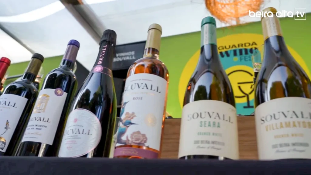 Garrafas de vinho e espumante da gama Souvall, da LAFerraz (DOC Beira Interior), em exibição num balcão de degustação no evento Guarda Wine Fest, realçando os rótulos de vinhos de altitude e viticultura de montanha.
